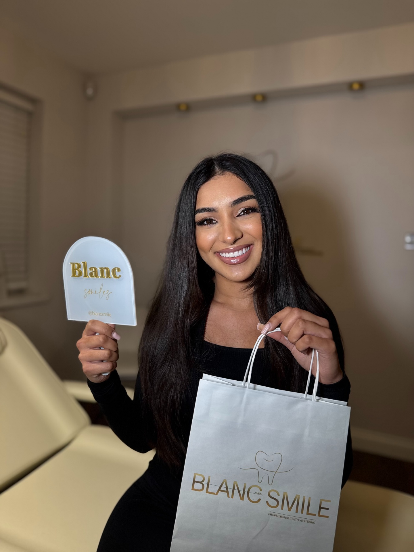 Blanc Smile specialist preparing a teeth whitening treatment in front of the gold studio logo