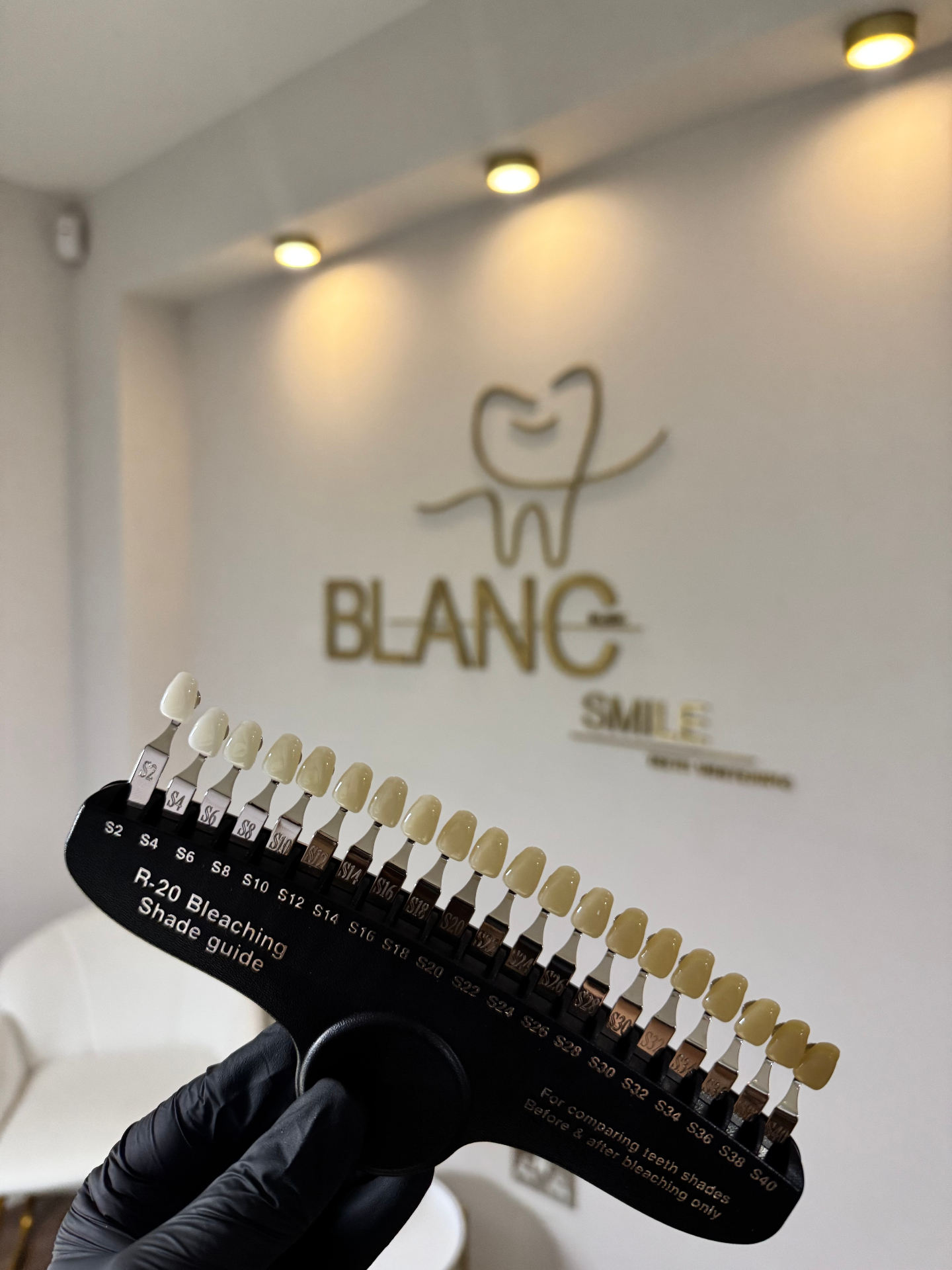 Blanc Smile shade guide held up in front of the gold studio logo