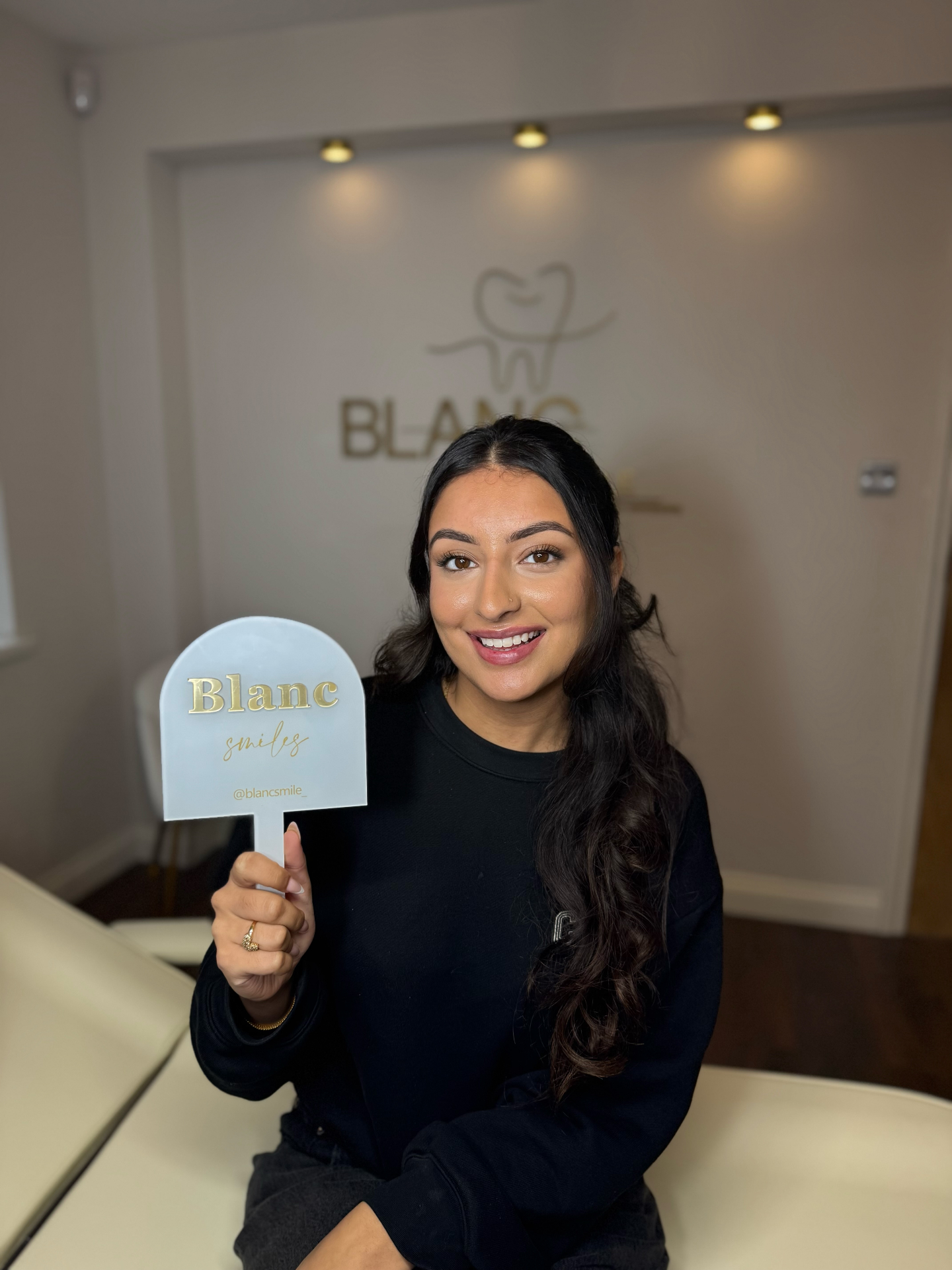 Client holding the signature Blanc Smile hand mirror in the treatment room
